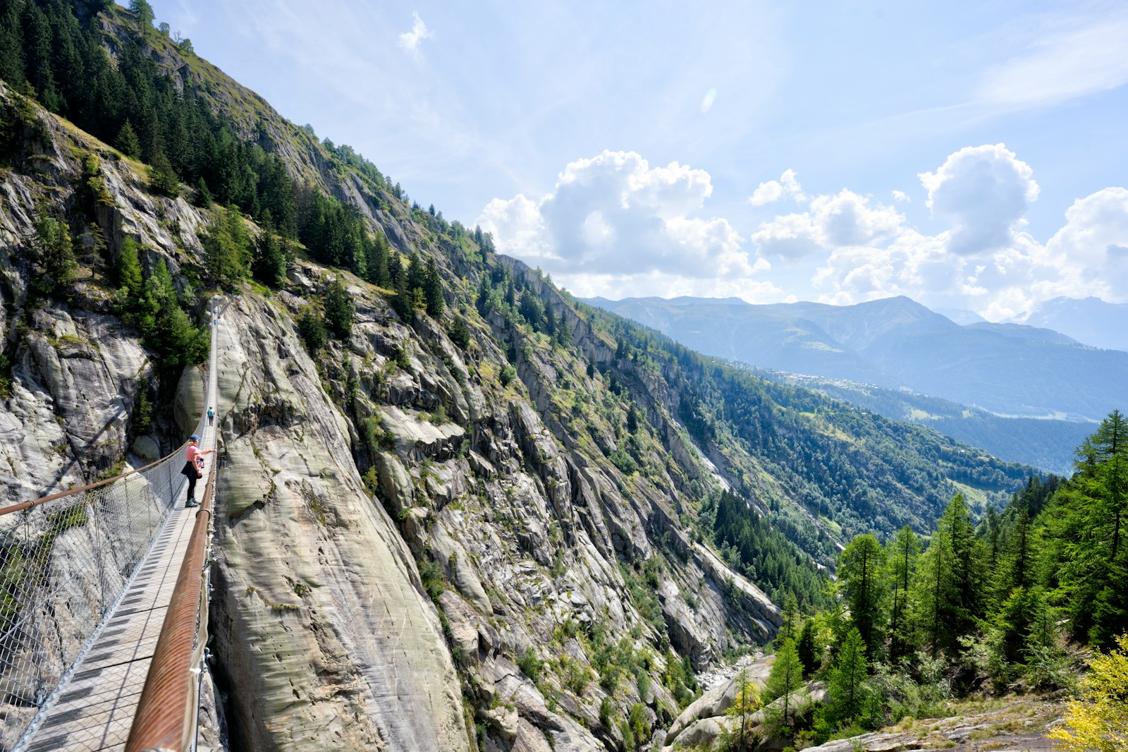 a person walking on a bridge over a mountain